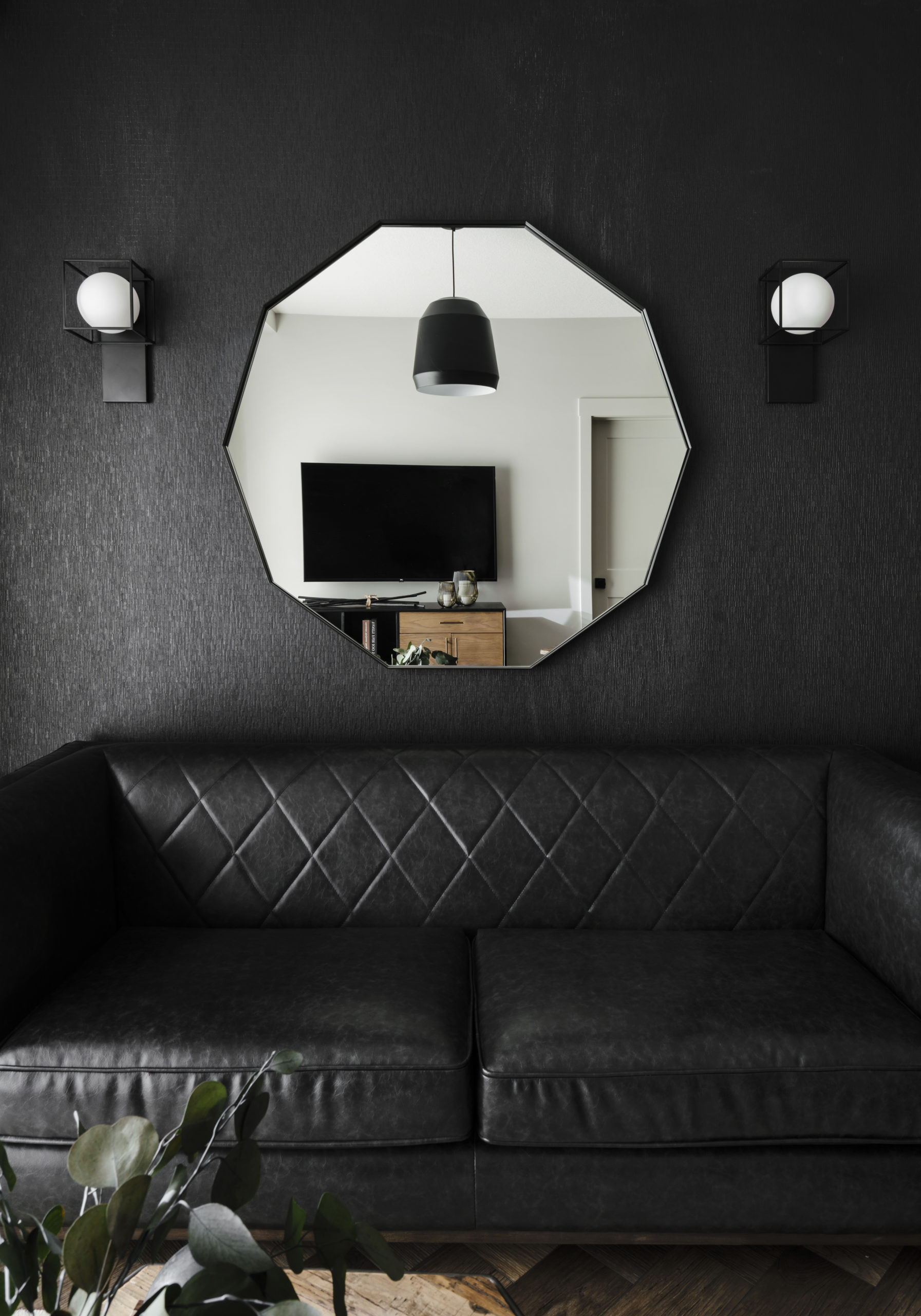 Black wallpaper with decagon mirror and wall sconces